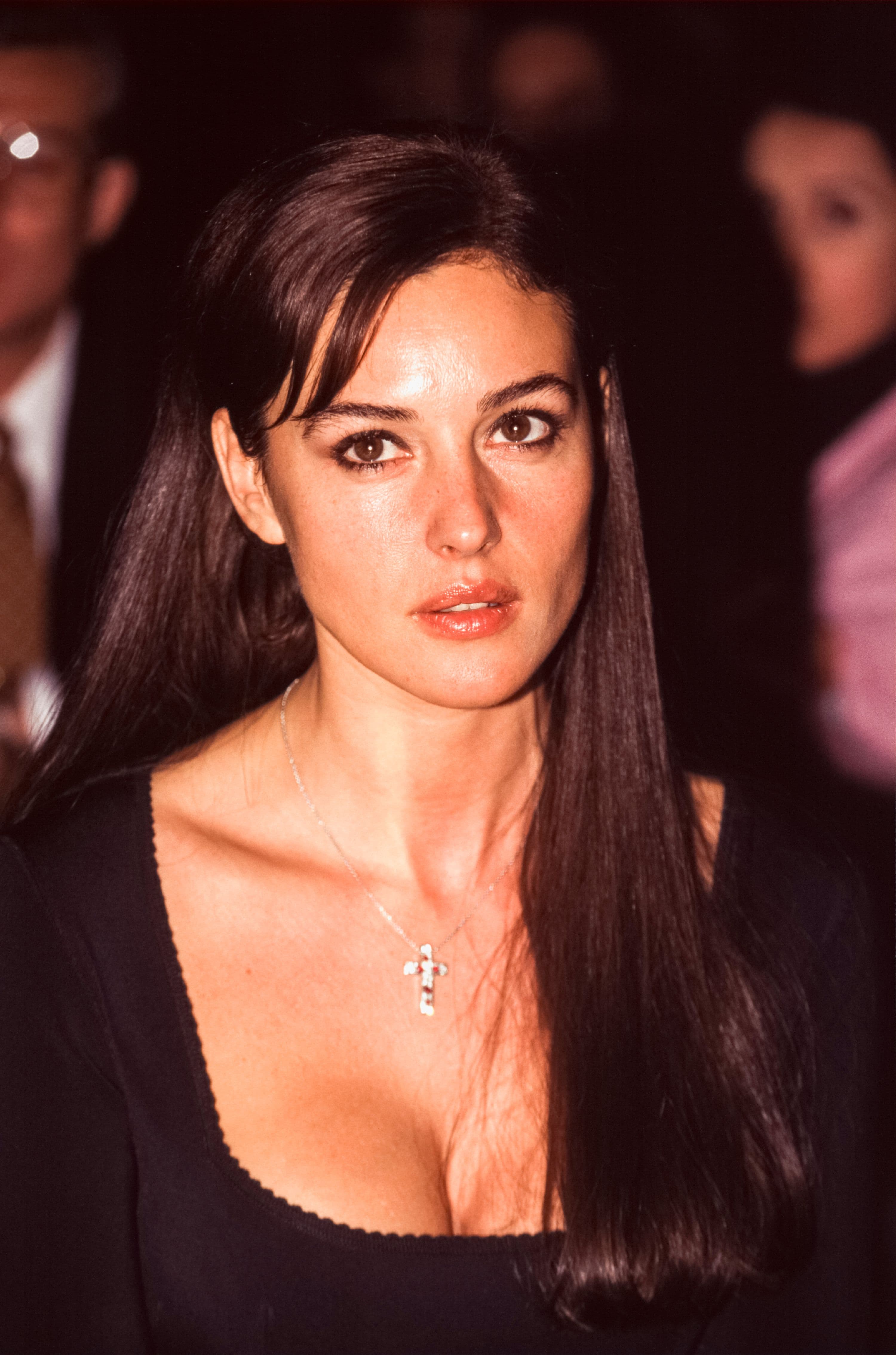 In London, Monica Bellucci walks the red carpet in a plunging black look finished with a small crucifix necklace.