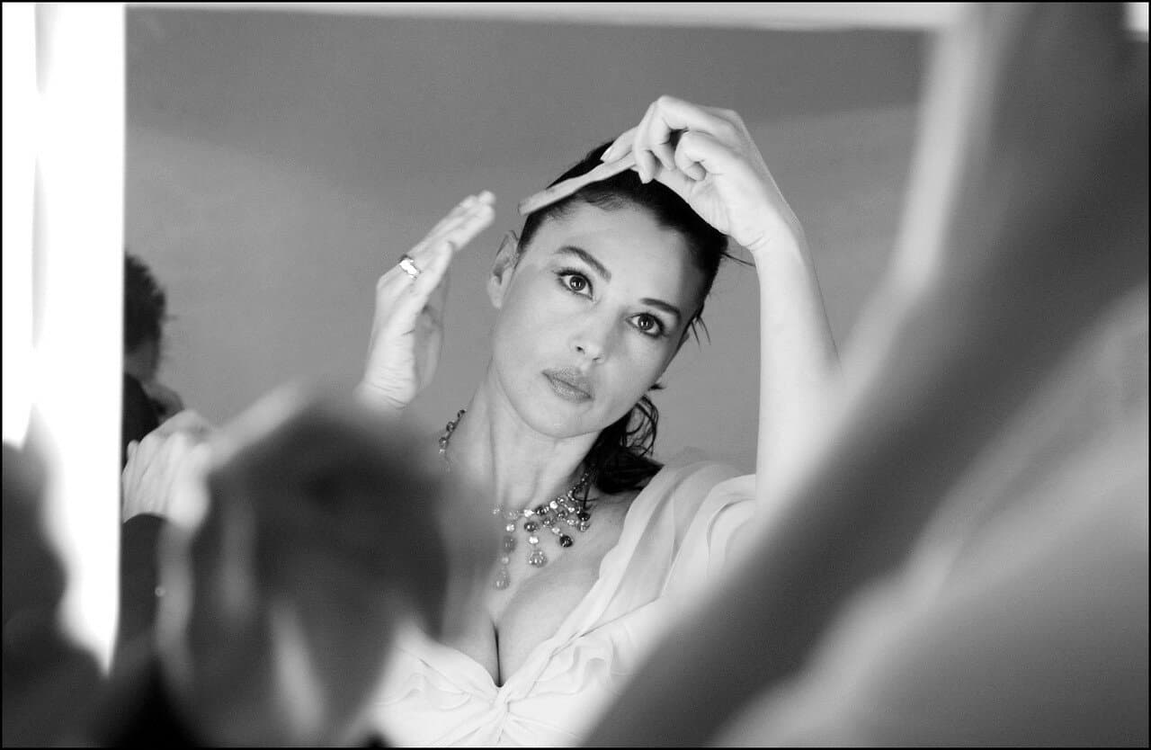 A mirror captures Bellucci adjusting her hair before stepping into the spotlight at Cannes.