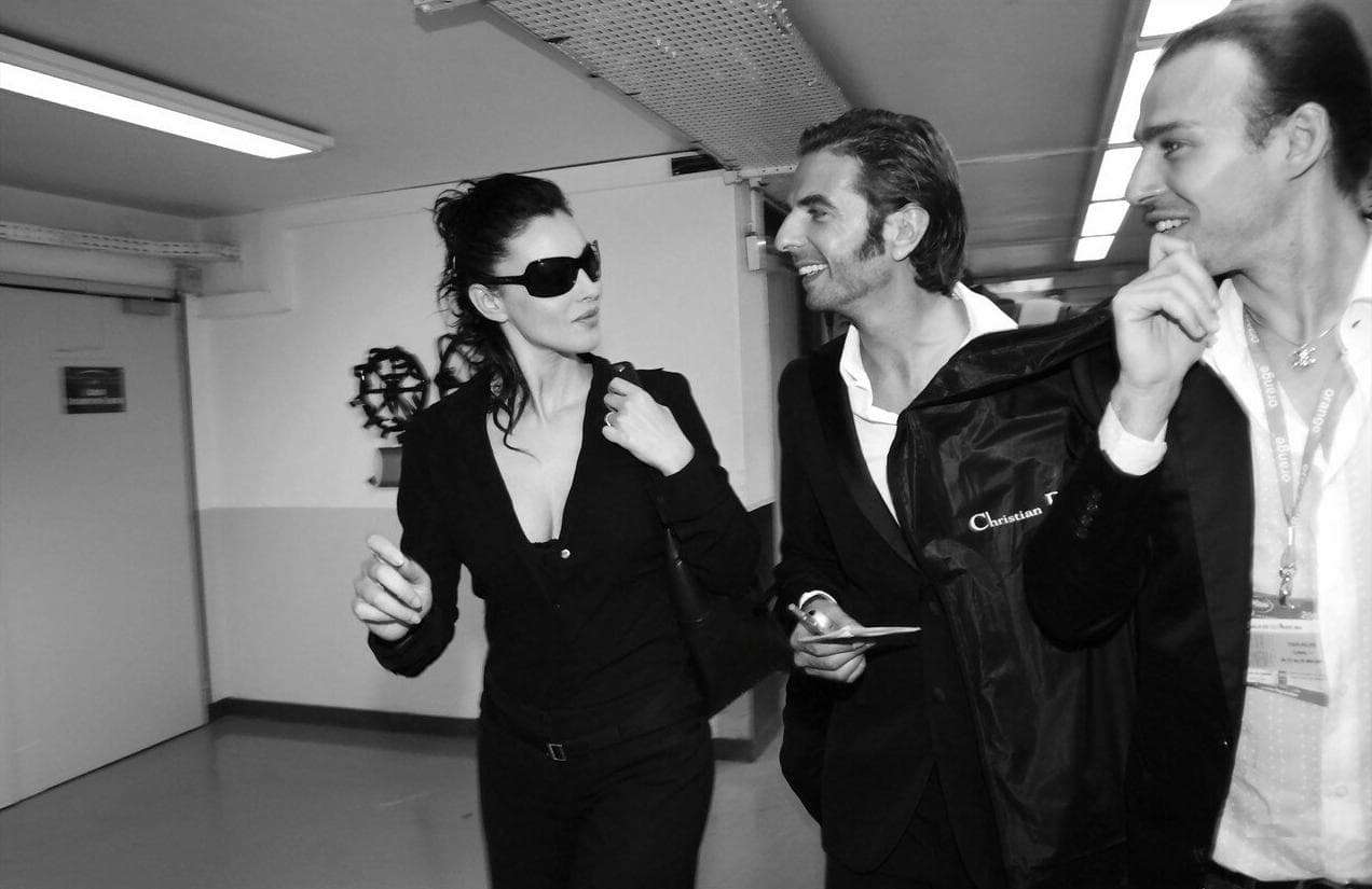 Wearing dark tailoring and sunglasses, Bellucci moves through the busy backstage area.