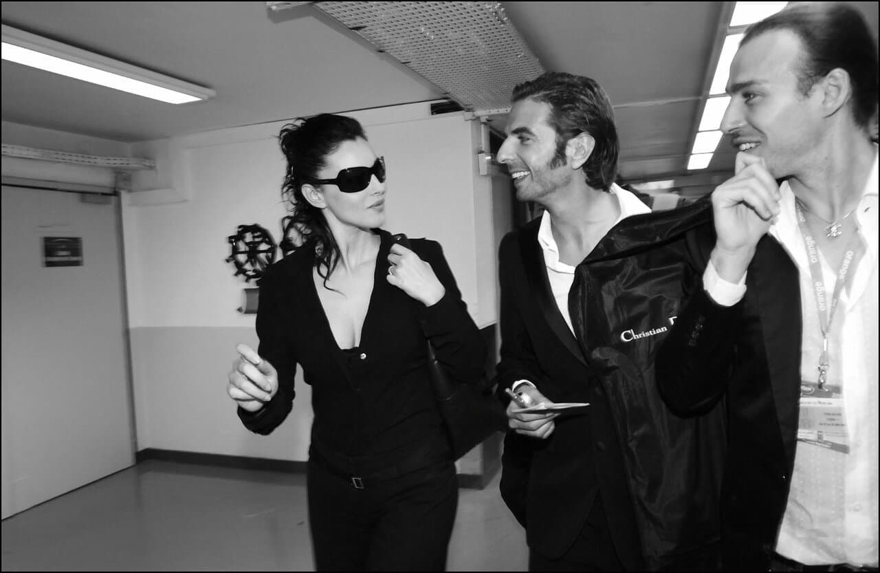 Wearing dark tailoring and sunglasses, Bellucci moves through the busy backstage area.