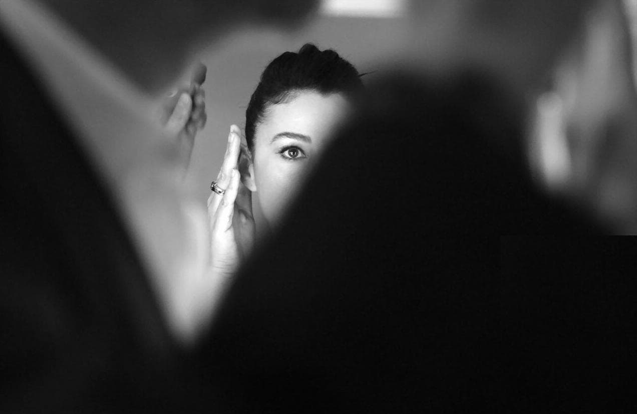 A close backstage composition frames Bellucci during a makeup check.