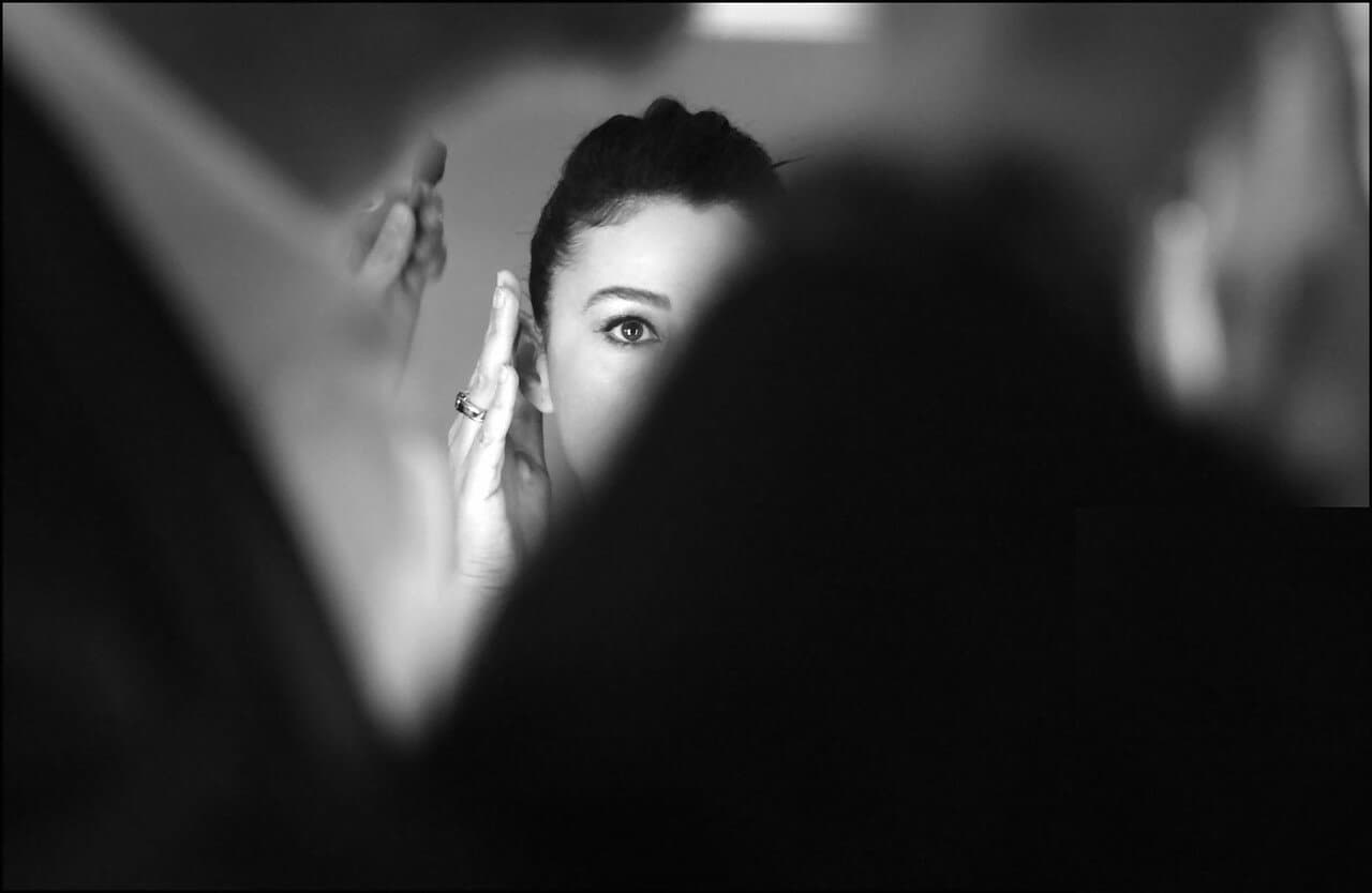 A close backstage composition frames Bellucci during a makeup check.