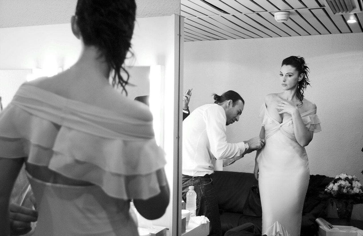 The gown is fitted and smoothed in front of the dressing-room mirror.