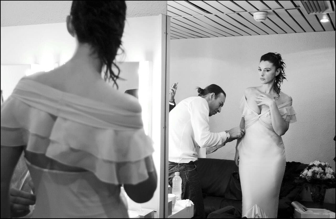 The gown is fitted and smoothed in front of the dressing-room mirror.