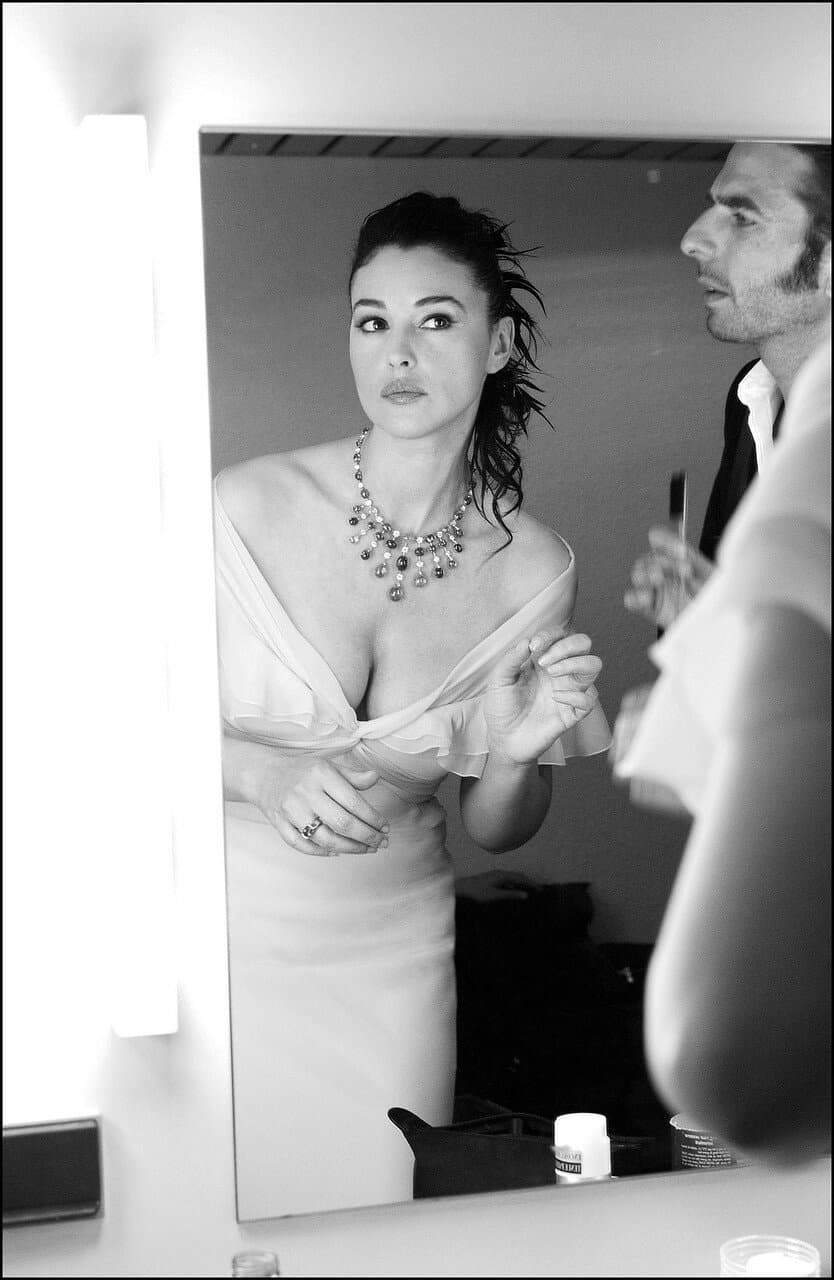 Bellucci studies her reflection while the backstage team completes the final details of her look.